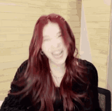 a woman with red hair is laughing and looking at the camera .