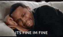 a man is crying while laying on a couch .