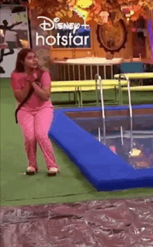 a woman in pink pajamas is standing in front of a pool .