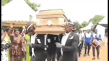 a group of men are carrying a coffin while dancing .