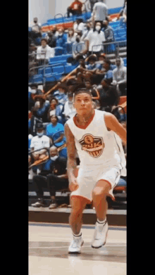 a basketball player is dribbling the ball on a court while a crowd watches .