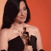 a woman in a black dress is holding an oscar award