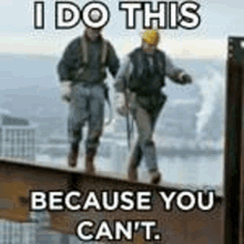 two construction workers are walking on top of a beam .