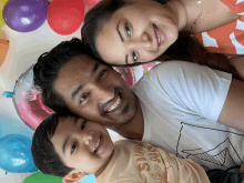 a family posing for a picture with balloons in the background and a boy wearing a shirt that says sunny