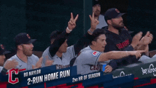 a group of baseball players are sitting in a dugout with a sign that says " 2 run home run "