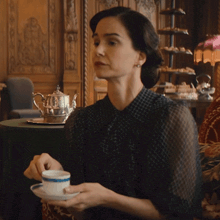 a woman sitting at a table holding a cup of coffee