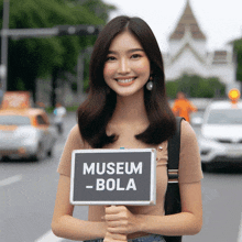 a woman holds up a sign that says museum - bola