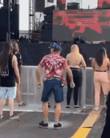 a man in a pink shirt and blue shorts is dancing in front of a crowd at a music festival .