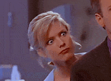 a woman with blonde hair is looking at a man in a black suit