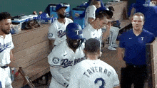 a group of baseball players are standing in a dugout and one of them is wearing a number 2 jersey .