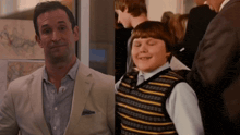 a man in a suit and a boy in a striped vest are next to each other