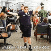 a police officer is dancing in an office with his arms outstretched in front of a crowd of people .