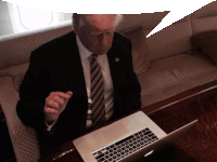 a man in a suit and tie is pointing at a laptop