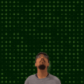 a man with glasses stands in front of a green background with the numbers 7 and 17 above him