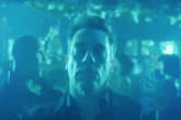 a man in a blue shirt is standing in front of a crowd
