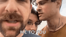 a man with a beard and glasses is standing next to a woman and another man .