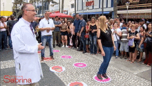 a man in a lab coat stands in front of a crowd of people with the word sabrina on the bottom