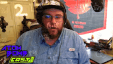 a man wearing headphones and glasses is sitting in front of a poster that says ad victoriam