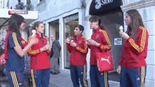 a group of women eating ice cream in front of a store that says ' 3 store ' on it