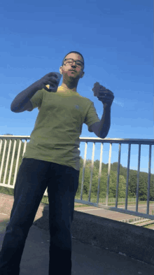 a man in a green shirt is standing on a bridge holding something