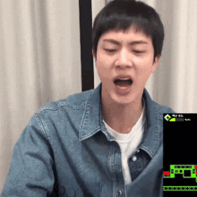 a man in a denim jacket is playing a video game with a green screen that says music