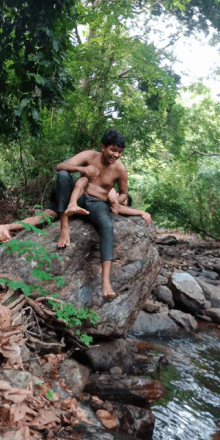 a man sitting on a rock with a child on his lap