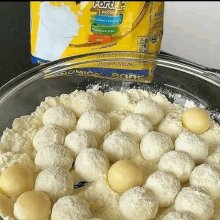 a bowl filled with white balls of powdered milk next to a bag of powdered milk .