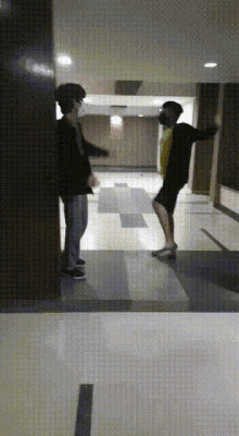 a man wearing a mask is dancing in a hallway with another man