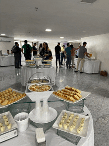 a group of people are gathered around a buffet table filled with food