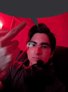 a young man wearing glasses and a headset giving the middle finger