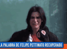 a woman is crying in front of a green board and a sign that says la palabra de felipe pettinato recuperado