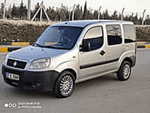 a silver minivan is parked on the side of the road .