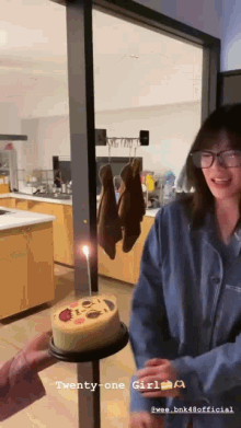a woman is holding a cake with a smiley face on it