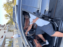 a man in a white shirt is sitting in a car with the door open