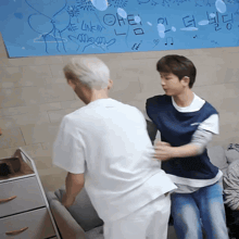 two men are standing in front of a wall with drawings on it and one of the drawings says oh