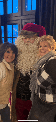 three women pose for a picture with santa claus