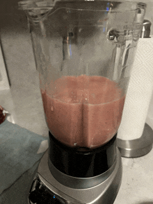 a blender filled with a pink liquid and a paper towel on the side