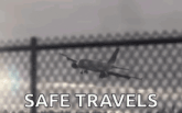a plane is flying over a fence with the words `` safe travels '' written on the bottom .