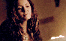 a woman in a dark room with a candle in the background