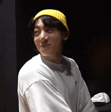 a person wearing a yellow beanie and a white shirt with the word nike on it