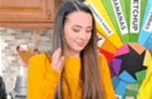 a woman in a yellow sweater is standing in a kitchen next to a bunch of ketchup bottles .