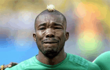 a soccer player with a mohawk is crying while wearing a green jersey .