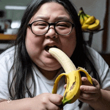 a woman with glasses is eating a banana with her tongue sticking out .