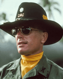 a man wearing a cowboy hat and sunglasses has the letter x on his sleeve