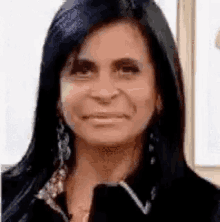 a close up of a woman 's face with long black hair and earrings .