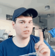 a man wearing a baseball cap and a blue shirt is pointing