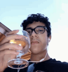 a young man with glasses is holding a glass of wine