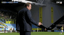 a man in a suit stands on a soccer field in front of a banner that says " edward sturing "