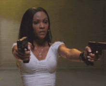 a woman is pointing two guns at the camera .