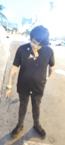 a man wearing a black shirt and black pants is standing on a sidewalk